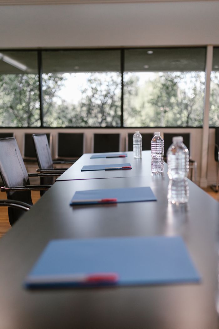 A modern conference room setup with chairs, water bottles, and notebooks on a wooden table.