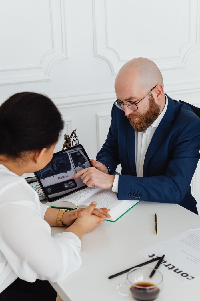 Two professionals discussing a project using a digital tablet in a modern office.